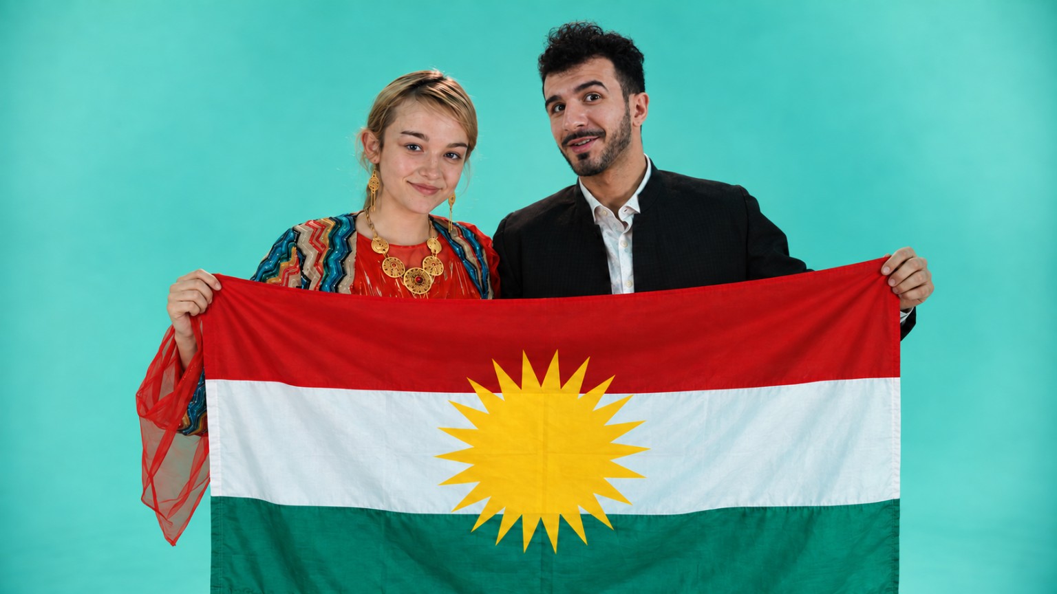 Aram Shkur and a performer holding the Kurdistan flag against a turquoise backdrop